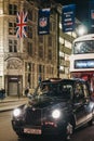 Black taxi and bus on Regent Street, London, under NFL flags, in the evening Royalty Free Stock Photo