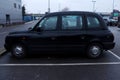 Black taxi in a parking lot in England