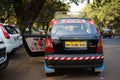 Black taxi on a Mumbai street surrounded by trees and cars