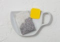 Black tea tea bag with yellow tag on ceramic plate with cup shape on light Royalty Free Stock Photo