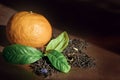 Black tea with bergamot is scattered in the shape of a circle. Mandarin and three green leaves adorn the composition. Royalty Free Stock Photo