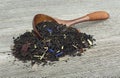 Black tea with dried fruits and petals in wooden spoon on wooden table Royalty Free Stock Photo