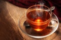 Black tea freshly brewed in a glass cup, steaming hot drink on d