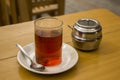 A black tea in a glass cup on a saucer with a spoon on a wooden table with a metal sugar bowl Royalty Free Stock Photo