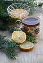 Black tea, honey, lemon slices on old wooden board, fir tree ar