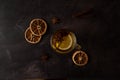 Black tea with lemon slices, star anise and cinnamon in a glass teacup on a black metallic background. Top view