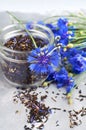 Black tea mix with dried cornflower petals and thyme in glass jar with fresh cornflowers