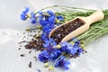 Black tea mix with dried cornflower petals and thyme in wooden scoop, fresh cornflowers bouquet.