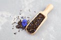 Black tea mix with dried cornflower petals and thyme in wooden scoop. Herbal tea