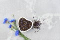 Black tea mix flat lay with dried cornflower petals and thyme in ceramic bowl. Herbal tea