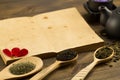 Black teapot, cups, tea collection, flowers, old blank open book on wooden background. Menu, recipe