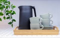 Black teapot and green cups with a saucers on a wooden tray