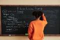 Of black teenage girl writing on blackboard in school classroom Royalty Free Stock Photo