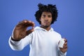 Black teenager holding jar of tablets and showing one pill over blue studio background, selective focus