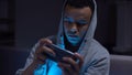 Black teenager playing video games on phone, harm for mental health and eyesight