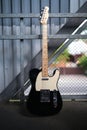 black telecaster shaped electric guitar stands on the street