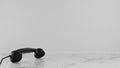 Black telephone ear plank on the black and white marble floor in the room, the background is rough white.