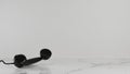 Black telephone ear supine on the black and white marble floor in the room, the background is rough white. Royalty Free Stock Photo