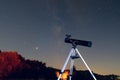 Black telescope reflector on a tripod in starry night sky scene