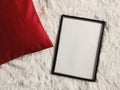 Black thin wooden frame with blank copyspace as poster photo print mockup  red cushion pillow and fluffy white blanket  flat lay Royalty Free Stock Photo