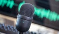 Black tilted condenser microphone, mic blur turquoise waveform background