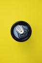 Black tin can with a gold key ring on a bright yellow background without people close-up view from above Royalty Free Stock Photo