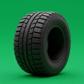 Black tire with chunky tread pattern is displayed against a vibrant green background. Royalty Free Stock Photo