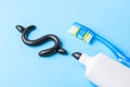 Black toothpaste from charcoal for white teeth. Tooth-paste in the form of dollar sign, tube and dental counter on blue Royalty Free Stock Photo