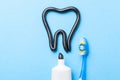 Black toothpaste from charcoal for white teeth. Toothpaste in the form of tooth, tube and toothbrush on blue Royalty Free Stock Photo
