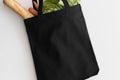 Black tote bag mockup with groceries on a white table