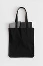 Black tote bag mockup with notebooks on a white table