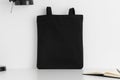 Black tote bag mockup with workspace accessories on a white table