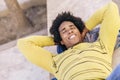 Black tourist with afro hair lying on the ground outdoors.