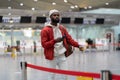 Black tourist man waiting to check in in airport terminal, stands with suitcase, using smartphone. Royalty Free Stock Photo