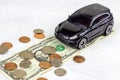 Black toy automobile with usa dollar coins on light background. Car insurance, auto service and repair, transport tax concept. Royalty Free Stock Photo