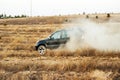 Black Toyota Prado SUV rides in the field in the rays of the sunset