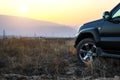 Black Toyota Prado SUV rides in the field in the rays of the sunset