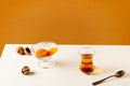 Black traditional Turkish tea in a glass cup and dried fruits on a white table. Royalty Free Stock Photo