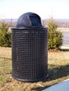 Black trash can by trees Royalty Free Stock Photo