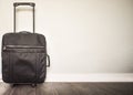 Black travel bag on the dark wooden floor with white wall in the background and free copy space Royalty Free Stock Photo