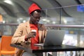 Black traveler man sitting at cafe in airport work on laptop, waiting a boarding, drinking coffee Royalty Free Stock Photo