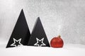 Black triangles of Christmas tree with white stars and red shiny ball on the snow. Defocus background. New Year