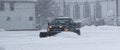 Black truck with a snowplow clearing a parking lot behind buisnesses Royalty Free Stock Photo