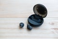 Black true wireless earbuds with the power bank case on the wooden background Royalty Free Stock Photo