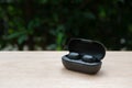 Black true wireless earbuds with power bank case on wooden table with green background Royalty Free Stock Photo