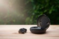 Black true wireless earbuds with power bank case on wooden table with green background Royalty Free Stock Photo