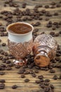 Black Turkish coffee in copper cup and roasted coffee beans scattered on wooden table. Traditional Turkish coffee in copper cup Royalty Free Stock Photo