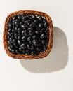 Black Turtle Bean legume. Wicker basket with grains. Top view, h