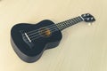 Black ukulele on white wood table background, Blank copy space. Music concept. Hawaiian guitar