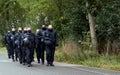 Black-uniformed police officers march in a paramilitary group in lockstep on a German country road